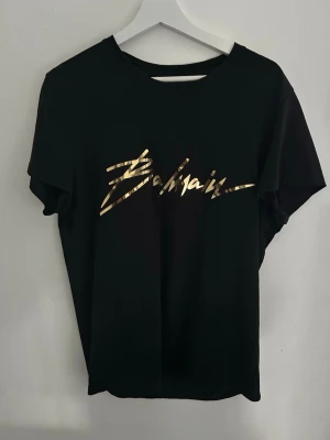 Svart Balmain t-shirt med guldtryck - En unik balmain T-shirt självklart äkta. Nypris ca 5000 kr storlek M