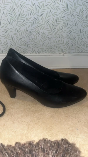 Svarta pumps med spetsig tå - Snygga svarta pumps från din sko  med spetsig tå och låg klack. Skorna är tillverkade i skinnimitation och har en klassisk, stilren design som passar till många olika outfits. Perfekta för dig som gillar enkel och elegant stil.