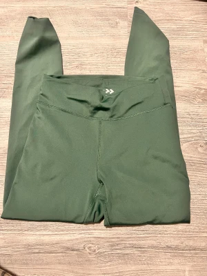 Mörkgröna leggings - Säljer ett par mörkgröna leggings med hög midja och stretchigt material. Perfekta för träning eller chill dagar. Snygg och enkel design som sitter skönt och följer kroppens rörelser.