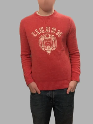 Röd stickad tröja från Morris Co - Säljer en röd stickad tröja från Morris Co med stort vitt tryck och emblem på bröstet. Tröjan har rund halsringning, ribbade muddar och är långärmad. Perfekt för dig som gillar klassisk och stilren look.