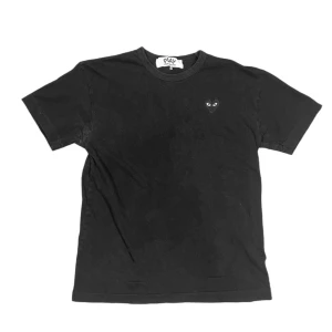 Comme des Garçons Play T-Shirt - Comme des Garçons PLAY is a line that was created as a collection by not designing. The t-shirt appears with a tonal simple heart logo attached.   Marked size: XL  (Please refer to measurements)  Pit to pit: 52cm Shoulder to shoulder: 50cm Sleeve length: 19cm Top to bottom: 68cm Condition: Used, pit stains