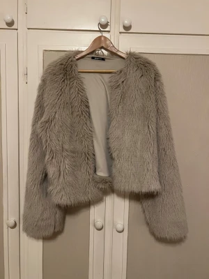 Beige pälsjacka - Säljer en fluffig och snygg beige pälsjacka från Gina Tricot i storlek XL. Jackan är bara använd 1-2 gånger då jag hittade en annan som passade mig bättre, därav i nyskick och den stängs med hyskor framtill.