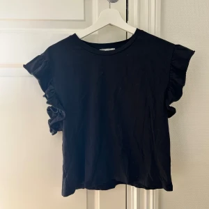 Svart topp med volangärmar - Svart t-shirt från Zara med volang ärm. 