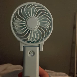 Bärbar Mini USB-fläkt - Smidig och portabel mini-fläkt i ljusblått, perfekt för resor eller skrivbordet. Drivs via USB och har ett enkelt knapptryck för att starta. Fläkten är i gott skick utan synliga skador eller slitage.