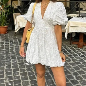 Vit klänning från Eva Jansson  - Superfin vit kortklänning med v-ringning och puffiga ärmar. Perfekt för studenten! Säljer pga att den inte passar mig. Helt oanvänd!💕