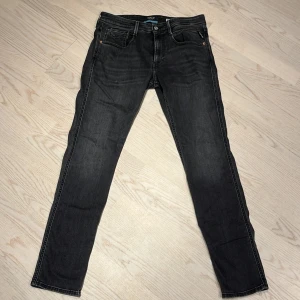 Replay Anbass svarta slim jeans 33/32 - Svarta jeans från Replay, modell Anbass med slim fit. Klassisk femficksdesign, svarta sömmar och diskret Replay-logga på bakfickan. Snygg, smal passform och stretchigt jeanstyg som sitter tajt men bekvämt. Perfekta för dig som gillar en stilren look. PRISET EJ HUGGET I STEN!