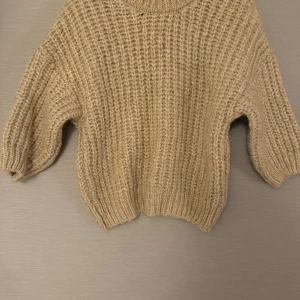 Beige stickad tröja med grov struktur - Säljer en beige stickad tröja med grov ribbad struktur och rund hals. lite loose passform och är perfekt för dig som gillar mysiga och trendiga plagg. Materialet känns mjukt och värmande, perfekt för kyliga dagar.