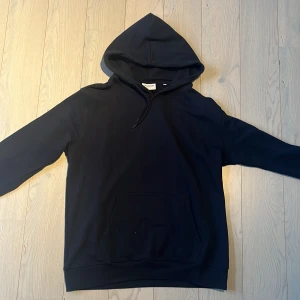 Svart hoodie från Lindbergh XL - Svart hoodie från Lindbergh i relaxed fit, storlek XL. Tröjan har huva med snörning, magficka och långa ärmar. Materialet är mjuk bomull och passformen är loose. Perfekt för chill dagar och enkel att matcha med jeans eller joggers. Använd 1 gång så 10/10 skick!