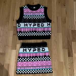 Mönstrad kortkjol från H&M Divided - Säljer en cool kortkjol från H&M Divided. Kjolen har ett grafiskt mönster med peace-symboler, schackrutor och text i svart, vit, rosa och lite turkos. Materialet är stickad syntet som känns mjukt och stretchigt. Perfekt för dig som gillar statement-plagg och färg!kjolen är i storlek xxs och tröjan xs nästan alldrig anndvänd!!!😁