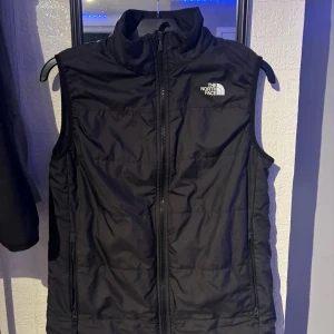 the north face väst - En skön väst som gör sitt jobb och är snygg, men den är lite sliten man ser tecken på att den e använd men ställ frågor om du undrar något (: Storlek är L på barn men S på ungdom 