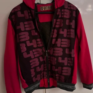 Röd bomberjacka med tryck - Säljer en unik bomberjacka från Zity i rött med stort grafiskt tryck av siffran 43 över hela jackan. Jackan har använts många gånger 