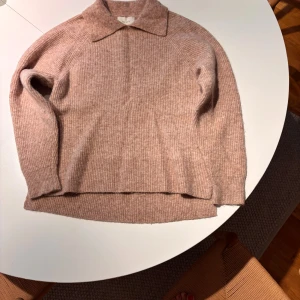 Beige stickad tröja från Neo Noir - Mysig beige stickad tröja från Neo Noir med klassisk krage och långärmad design. Tröjan är ribbad och tillverkad i en mjuk mix av alpacka, ull, polyamid och elastan. Perfekt för dig som gillar en chill och stilren look.