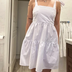 Poplinklänning - stradivarius  - Supersöt vit klänning från Stradivarius med knytband på axlarna och volangkjol. Modellen är ärmlös med fyrkantig urringning och öppen rygg.      Jag är S/36 & 170cm för referens och klänningen sitter perfekt! Dragskedja på sidan.