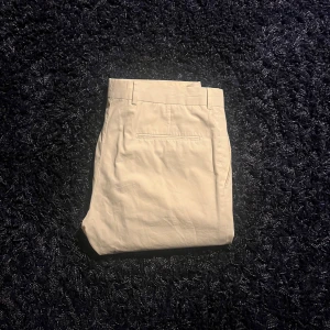 Vita kostymbyxor från Tiger of Sweden - Snygga vita kostymbyxor från Tiger of Sweden med klassisk passform och diskret bakficka. Byxorna har hällor för bälte och är tillverkade i ett mjukt bomullsmaterial. Perfekta för en clean och stilren look.