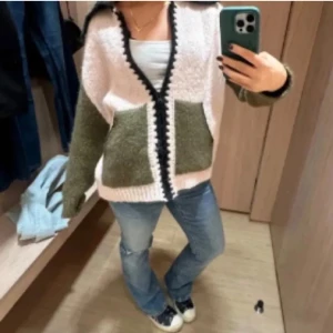 Stickad kofta från Zara slutsåld rosa grön - Säljer en mysig stickad kofta med beige kropp och olivgröna ärmar och fickor. Koftan har svart kant längs knäppningen och kragen, samt två stora fickor framtill. Perfekt för dig som gillar chill och unik stil. Slutsåld as snygg kofta. Väldigt populär!!!❤️