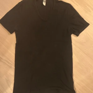 Svart v-ringad t-shirt från G-Star RAW - Svart t-shirt från G-Star RAW i storlek M. Modellen har v-ringad hals och korta ärmar, tillverkad i mjuk bomull som känns skön mot huden. Perfekt för dig som gillar stilrena och enkla plagg med snygg passform.