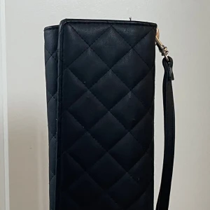 Svart plånbok - Stor svart plånbok från Glitter, Fint skick men några små defekter som en lös tråd (se bild), Cirka 25cm lång och hållaren för mobilen är Cirka 14x7cm