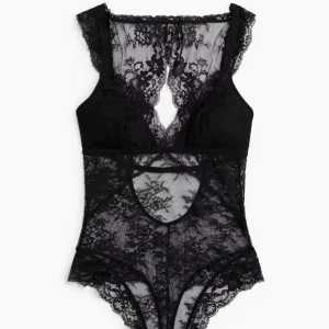 Svart spetsig stringbody - Säljer en svart stringbody i spets med djup v-ringning och breda axelband. Bodyn har även fina spetsdetaljer och endast använts 2 gånger då den köptes för en vecka sen🥰