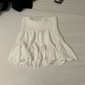 Vit volangkjol från 157, XS - Supersöt vit kortkjol från 157 i storlek XS. Kjolen har smockad midja och flera volanglager som ger en flowy och luftig känsla. Perfekt för varma dagar och enkel att styla med crop tops eller linnen. Pris kan diskuteras🥰