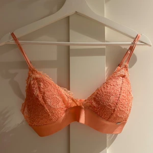 Korallfärgad spets bralette från Lindex - Superfin korallfärgad bralette från Lindex med blommig spets och justerbara axelband. Mjuk resår under bysten och hakknäppning bak. Perfekt för dig som gillar en feminin och bekväm look.
