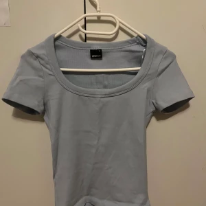 Ljusblå topp från Gina Tricot - Aldrig använt då de aldrig kommit till användning. Passar även t mig som egentligen brukar ha xxs/xs.  TAR EMOT PRISFÖRSLAG!! En ljusblå topp från Gina Tricot i storlek S. Toppen har rund halsringning och korta ärmar, tillverkad i mjuk bomull. Perfekt för dig som gillar enkel och stilren design med en fräsch färg. Passar dig som vill ha en basic topp i garderoben.