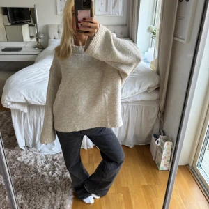 Beige oversized stickad tröja - Supermysig beige stickad tröja med oversized passform och breda, långa ärmar. Tröjan har ribbade muddar vid hals, ärmslut och nederkant. Perfekt för att chilla hemma eller när du vill ha en chill vibe. Snygg att styla med jeans eller leggings.
