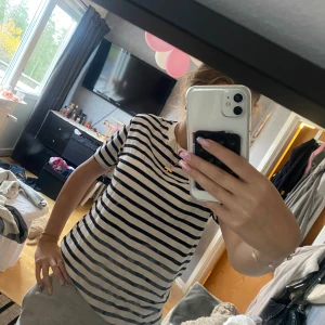 Randig t-shirt i bomull - Säljer en klassisk vit t-shirt med svarta horisontella ränder. T-shirten har rund halsringning och korta ärmar. Tillverkad i mjuk bomull, perfekt för en chill och stilren look.