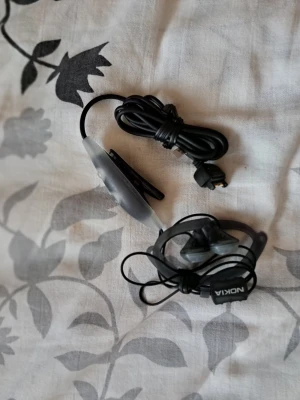 Nokia in-ear hörlurar pop-port uttag - Säljes:  Ett par äldre Nokia in-ear hörlurar. Perfekt för den som behöver ett extra par eller vill ha ett par klassiska hörlurar. Har in-ear-hörlurar med mjuka gummitoppar. Utrustat med en pop-port-kontakt. Den har en klämma för fastsättning på kläder. Kompatibilitet: Detta headset är gjort för äldre Nokia-telefoner som: Nokia 6230, 6230i Nokia 6610i Nokia 6020, 6070 Andra modeller med Pop-Port uttag.   Skickas via posten men köpare står för frakten. Ingen återköp eller retur! 