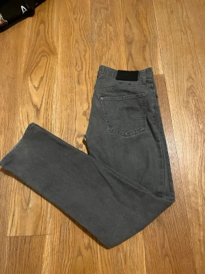 Gråa J Lindeberg jeans - Gråa jeans från J Lindberg i slim passform med raka ben. Storlek 31/32 och sitter likt Nudie jeans.  Finns en lagning i gylfen som jag kan skicka bilder på, men inget som märks vid användning. Annars bra skick! 