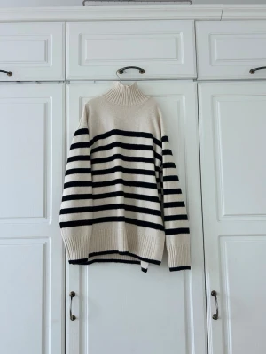 Randig polotröja från H&M XS💖💖💖 - Säljer en beige och svart randig polotröja från H&M i storlek XS. Tröjan har hög ribbad krage, långa ärmar och breda muddar vid ärmslut och nederkant. Stickad i mjukt material och har en loose passform som är perfekt för kyliga dagar.