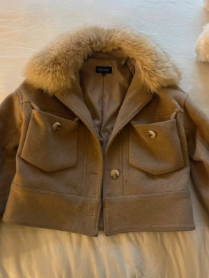 Beige jacka med päls från Meotine - Säljer en beige jacka från Meotine med päls. En knap är bort och en som är lite lös men annars är jackan i bra skick. Storlek xs/s
