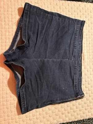 Mörkblå denimshorts Forever 21 - Säljer ett par mörkblå denimshorts från Forever 21 med klassisk femficksdesign och dragkedja i sidan. Shortsen har en loose passform och är tillverkade i bomull. Perfekta för dig som gillar enkel och stilren look.