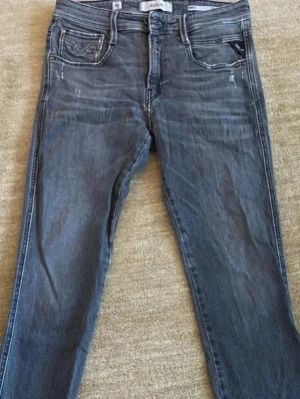 Replay jeans - Säljer nu mina replay anbass jeans som är i en grå färg (slim fit). Skick: 9-10, jeansen är använda men inga defekter (slitningarna en del av designen). Strlk: 28/30 (midja/längd). Nypris: 1600. Mitt pris: 799.  Tveka inte på att höra av dig! 