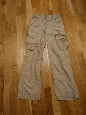 Beiga cargo byxor  - Beiga cargo byxor helt utan defekter. Stretchiga i midjan och låga till medelhöga. 