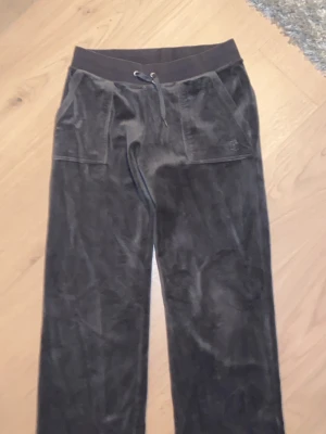 Svarta mjukisbyxor Juicy Couture M - Säljer ett par svarta mjukisbyxor från Juicy Couture i storlek M. Byxorna har bred resår i midjan med snörning och är gjorda i mjuk sammet. Klassisk Juicy-logga på fickan och raka ben för chill vibe.