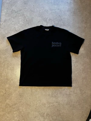 Svart Broken Planet t-shirt - Svart t-shirt från Broken Planet. I väldigt bra skicka även fast jag har haft den hyfsat länge så har jag hållit den i bra skick. Priset är inte hugget i stan så har du några funderingar så är det bara att ställa 