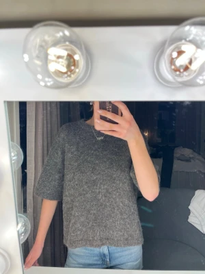 Grå stickad tröja från Gina Tricot - Mysig grå stickad tröja från Gina Tricot med halvkorta armar. Tröjan har en loose passform och är tillverkad i ett ullblandat material som känns både mjukt och varmt. ❤️stolen Xs