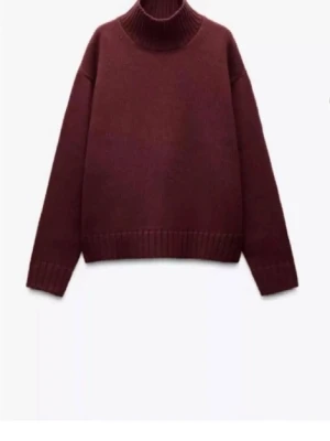 Vinröd polotröja från Zara - Säljer en vinröd polotröja med ribbad hög krage och muddar. Tröjan är stickad i mjuk ull och har en loose passform med långa ärmar. Perfekt att styla över en skjorta för en chill och snygg look.