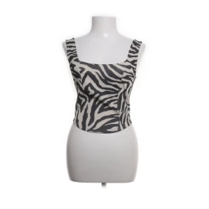 Zebramönstrad topp - Snygg topp med zebramönster i svart och vit. Modellen är croppad med breda axelband och fyrkantig urringning både fram och bak. Perfekt "finare" event eller till vardags. Samt lite dålt glitter i. 