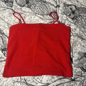 Röd linnetopp från Gina Tricot - Säljer en enkel och snygg röd linnetopp från Gina Tricot i storlek S. Toppen har smala axelband och är croppad i modellen. Materialet är mjuk bomull som känns skönt mot huden. Perfekt för dig som gillar färgstarka och stilrena plagg.
