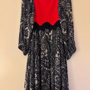 Chloé midilångklänning i viskos med spets och mönster - Unik midilång klänning från Chloé med röd överdel, marinblå  spetsdetalj i midjan och mönstrad kjol samt ärmar i mörkblått och vitt. Klänningen har långa, vida ärmar och en elegant, feminin siluett. Perfekt skick!