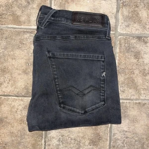 Replay Anbass jeans  - Svarta Replay Anbass jeans med klassisk femficksdesign och snygga detaljer på bakfickorna. Jeansen har en smal passform och är tillverkade i stretchig bomullsblandning för extra komfort. Midja 39cm, längd 104cm. JAG SKICKAR EJ FLER BILDER NÄR JAG BÄR JEANSEN! för storleksguide hänvisar jag till måtten och för bättre inblick i passformen rekommenderar jag att googla på modellnamnet. Jeansen kan vara uppsydda utan att jag noterat det så kolla måtten noggrant :) s4