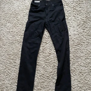 Svarta raka byxor från Zara - Svarta byxor från Zara i klassisk rak modell med fem fickor och knappstängning. Materialet är slitstarkt och har en lätt stretch för skön passform. Storlek 38.
