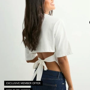 T-shirt med knytning i ryggen  - Vit T-shirt med knytning i ryggen från Nelly i storlek xs, inga täcken på användning