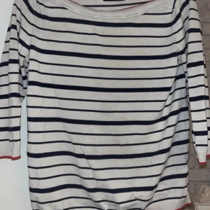 Randig tröja från Stockh LM i bomull - Säljer en vit och marinblå randig tröja från Stockh LM i storlek S. Tröjan har långa ärmar, ribbade muddar med röd kant och en bred halsringning. Materialet är mjuk bomull, perfekt för dig som gillar klassisk stil med en twist.