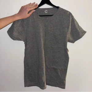 Grå basic t-shirt från Cubus - Enkel grå t-shirt från Cubus i mjuk ekologisk bomullsmix. Klassisk rund halsringning och korta ärmar. Perfekt till jeans eller shorts för en clean och chill look.