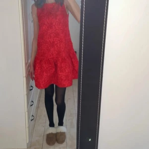 Röd ärmlös kortklänning med volang - Säljer en röd ärmlös klänning med volang nedtill och rund hals. Klänningen har ett subtilt mönster och är kort i modellen, jag är 168 för referens. Användes 1 gång förra julen. Ifrån ginatricot, nyskick. ❤️