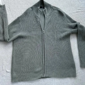 Grå stickad kofta med dragkedja - Säljer en grå stickad kofta med hel dragkedja framtill och ribbad struktur