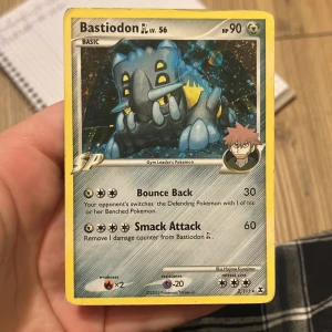 Bastiodon GL lv. 56 - Cool Pokémon-kort med Bastiodon GL från 2009! Perfekt för dig som samlar eller spelar Pokémon TCG. Kortet har unika attacker som Bounce Back och Smack Attack, och är illustrerat av Hajime Kusajima. Ett måste för alla Pokémon-fans och samlare! 