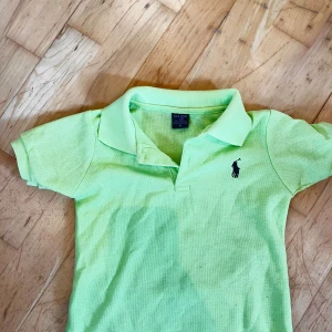 Ljusgrön pikétröja från Polo Sport - Fräsch ljusgrön pikétröja från Polo Sport i storlek S. Klassisk krage och korta ärmar, med den ikoniska Polo-loggan broderad på bröstet. Tillverkad i 100% bomull för en skön och luftig känsla. Perfekt för dig som gillar sportig och clean stil.